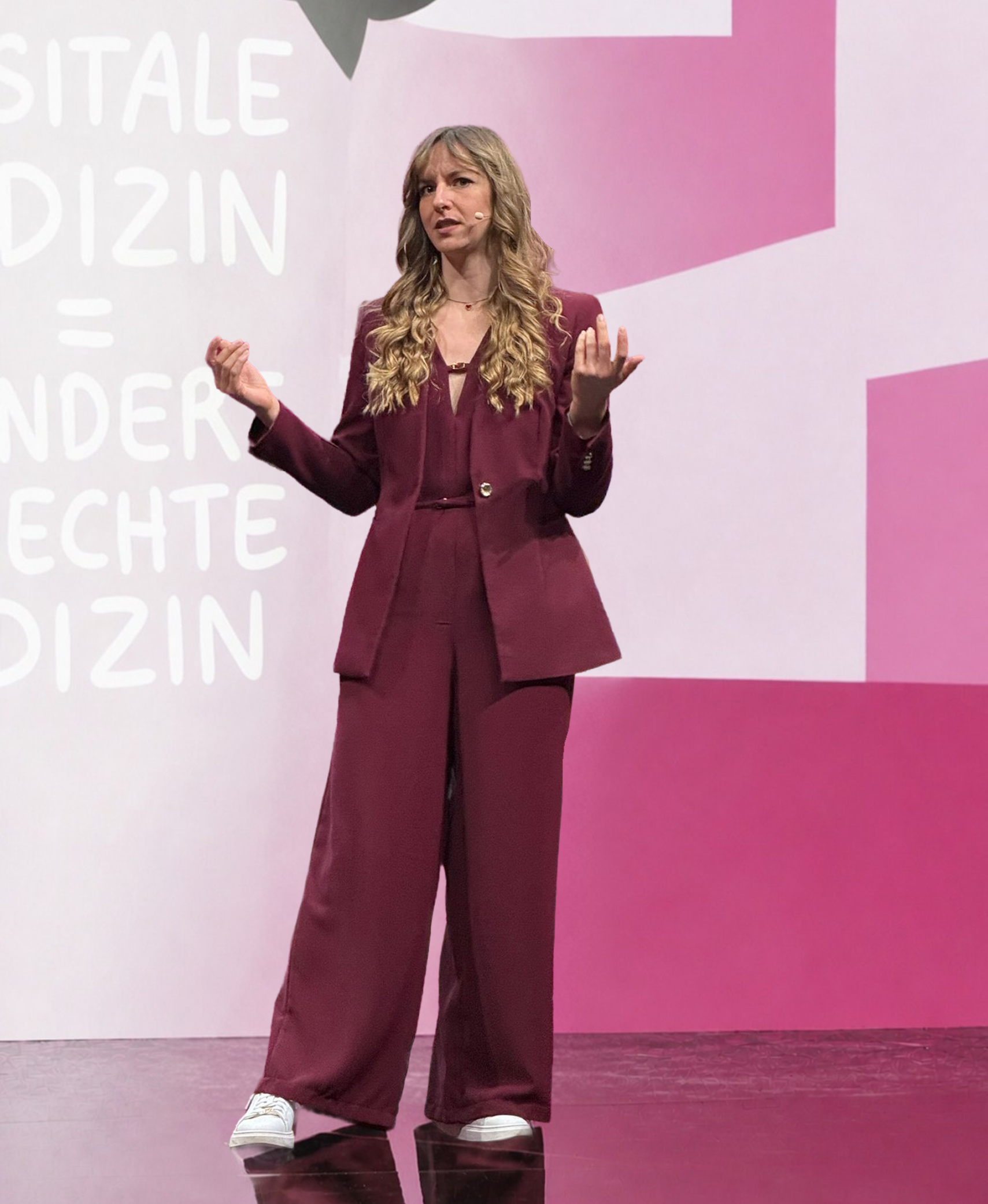 Beatrice Aretz speaking on a pink conference stage.